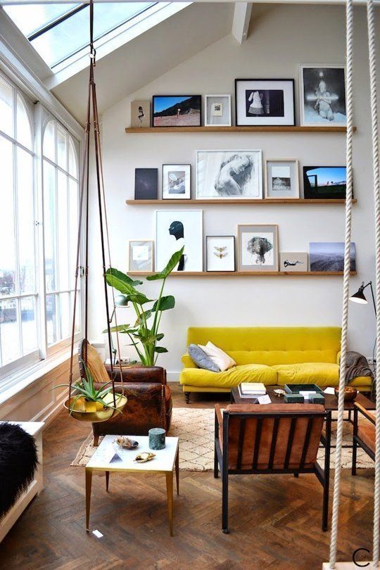 یک اتاق نشیمن دلباز با دیوار گالری تاقچه‌ای که تا سقف ادامه دارد و مبلمان زرد رنگ