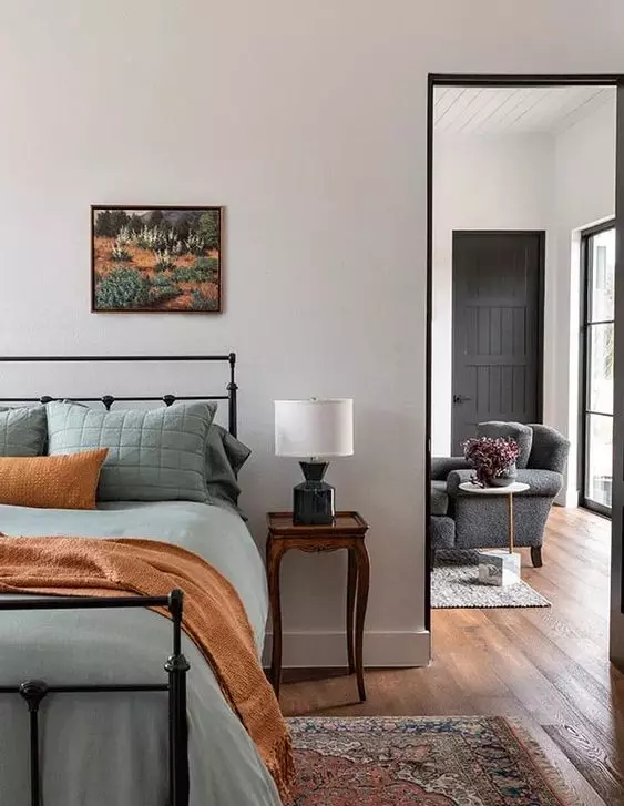 اتاق خواب مدرن با یک تخت فرفورژه مشکی با ملافه سبز